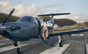 Photograph of a woman walking up steps of a Tradewind Airlines jet.