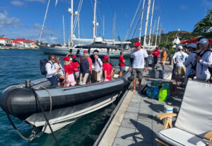A group of people standing dockside, preparing for a tour of the super yacht Maltese Falcon.