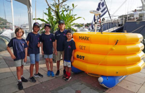 Five happy young sailors standing next to a robotic mark.